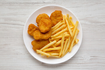 Tasty Fastfood: Chicken Nuggets and French Fries on a plate on a white wooden background, top view. Overhead, from above, flat lay.