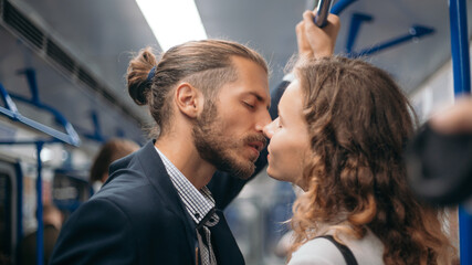 man and a woman in love kiss on a subway train.