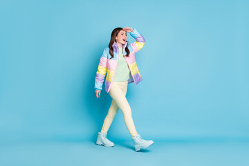 Photo portrait full body view of walking girl looking in distance with hand on forehead isolated on pastel blue colored background © deagreez