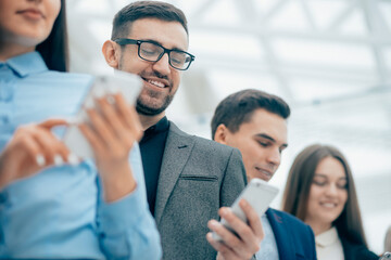 group of smiling business people looking at their smartphone screens