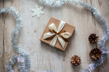 Beautiful Stylish Christmas brown gift on wooden background. Flat lay design. Christmas composition with gift and pines on wooden table.