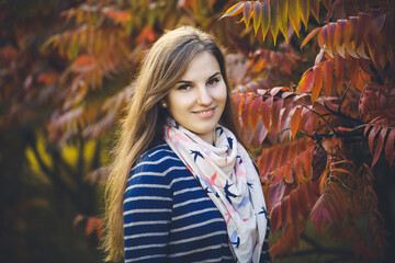 Beautiful woman in a blue dress standing in autumn nature with fallen leaves. Bright young...