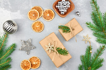 Gift boxes with Christmas decorations, dry oranges and green fir tree branches