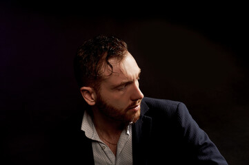 A man on a black background in a jacket and white shirt.Office style.