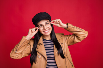 Portrait of attractive cheerful person hands touch glasses look empty space wear black hat isolated on red color background