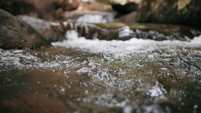 Slow motion of wild mountain river abundant clear stream flowing through rocks. Close-up of river rocks with flowing water. Close up