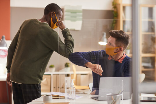 Portrait of two men touching elbows as contactless greeting in office