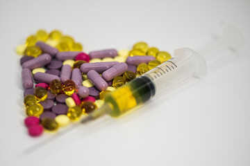 heart shaped pills and a syringe on a light background large