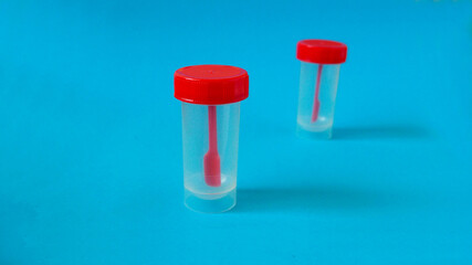 two closed clean plastic red containers for collecting feces on a blue background side view . fecal analysis