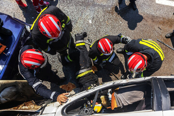 Firemen trying to release man from crashed car. There is a crashed cars in car accident.