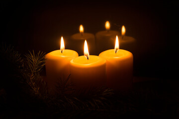 White candles with Christmas tree branches and Christmas tree toys on a dark background. The candle...
