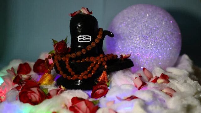 Diwali Black Shiva lingam figure on a white cottonwool litter with flashing lights with rudraksha beads, roses and glowing ball