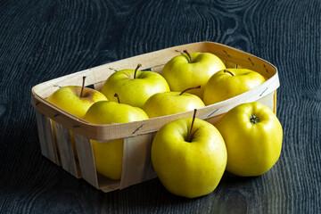 Pommes Golden dans une cagette en bois sur fond noir