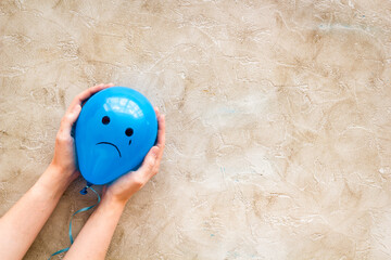 Sadness emotion face on balloon - depression mood background. Top view, copy space