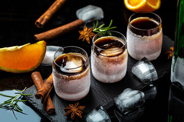 frozen herb liqueur in small glass. Shot glass of herb liqueur with cinnamon and oranges on a dark background