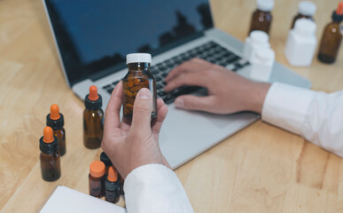 Doctors hold a bottle of medicine and print a record of patient information on a laptop computer in preparation to dispense medicine to patients who come to the hospital for ailments.