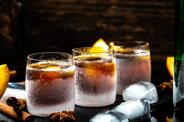 Frozen shot glass alcoholic drinks on rustic wood background. Shot glass of herb liqueur with cinnamon and oranges on a dark background, catering, banner, menu, recipe, place for text