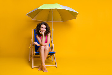 Photo portrait of dreamy girl sitting in blue deckchair under beach umbrella holding head glasses...