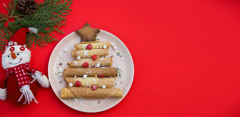 christmas food. Christmas tree made of food on a red background. New year symbol made of food. Copy space. Christmas tree made from wafer rolls.