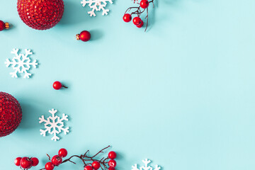 Christmas or winter composition. Frame made of snowflakes, balls and red berries on pastel blue background. Christmas, winter, new year concept. Flat lay, top view, copy space
