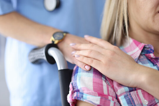 Woman in wheelchair holding a doctor's hand. Medical care and support concept