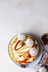 Vanilla cheesecake with carrot cake crust served with salty caramel topping and meringue, light concrete background. Selective focus. Top view. Copy space.