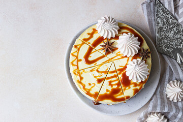 Vanilla cheesecake with carrot cake crust served with salty caramel topping and meringue, light concrete background. Selective focus. Top view. Copy space.