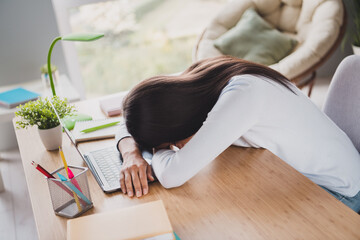 Photo of sleepy tired business woman sleep on desk laptop exhausted work from home inside living room indoors