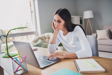 Photo of bored attractive businesswoman browsing laptop unhappy remote work indoors in house living...