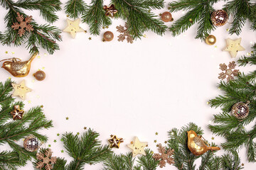 Fototapeta na wymiar Christmas frame made of fir branches and gold decorations on a white background. Copy space, top view, flat layer.