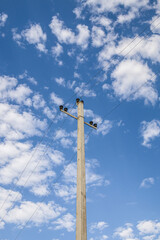 Electric concrete pole with wires. Background sky with light clouds. Metal constructions. Ceramic insulators.