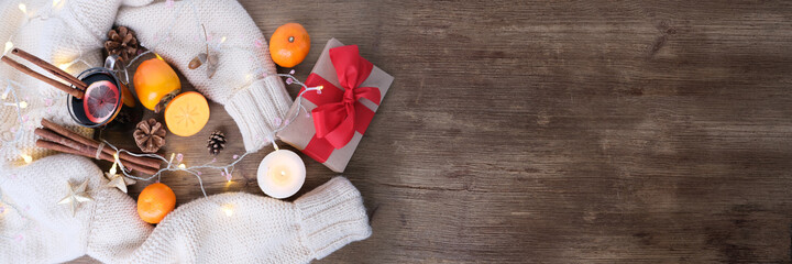 box with a gift in kraft paper with a red bow, a cup of hot mulled wine with lemon, fruits,...