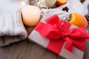 box with a gift in kraft paper with a red bow, a cup of hot mulled wine with lemon, fruits, candles, concept of merry christmas, cozy winter mood, holiday