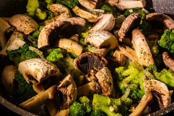 White champignons, onion and green broccoli fry on pan or wok. Hot delicious vegetarian dinner.