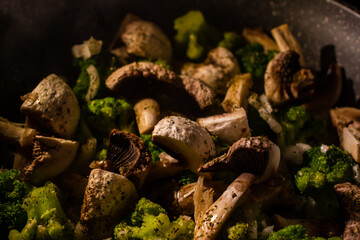 White champignons, onion and green broccoli fry on pan or wok. Hot delicious vegetarian dinner.