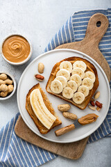 peanut butter banana sandwich in a white plate on gray background, top view