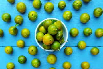 Yellow green calamansi, calamondin or philippine lime tropical fruit pattern in bright blue wood background. Asian summer citrus fruits flat lay composition.