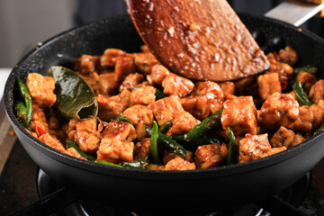 Making/Sauteeing  Orek Tempe, Indonesian Cuisine Made from Cubed Tempeh with Spice, Chilli, and Sweet Soy Sauce. Using Wooden Spatula, Home Cooking Process in the Kitchen