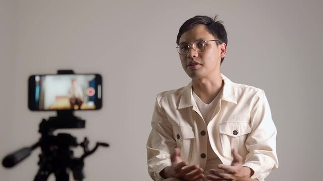 asian man filming video for introducing profile for online job application. male using mobile smart phone selfie recording answer of interview. man using hands gesture when talking in video.
