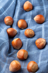 Top view of hazelnuts on blue cloth, with selective focus, vertical