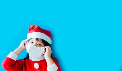 Fototapeta na wymiar Kid girl wear fabric mask protection covid19 with santa dress on christmas holidays party.Stay home good safe.Lockdown Covid-19 coronavirus.Social distancing.stay safe in winter.new normal.Blue banner