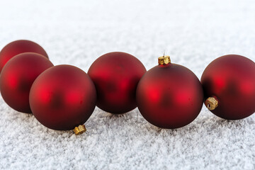 Red Christmas balls row on fresh snow. Frosty Xmas background. Merry Christmas and happy New Year.