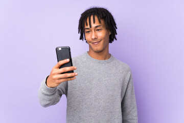 Young african american man isolated on purple background making a selfie