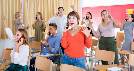 Fototapeta na wymiar Delighted Brazilian cheerful positive glad girl student talking on phone in auditorium with groupmates after successful passing exam