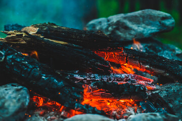 Vivid smoldered firewoods burned in fire close-up. Atmospheric warm background with orange flame of...