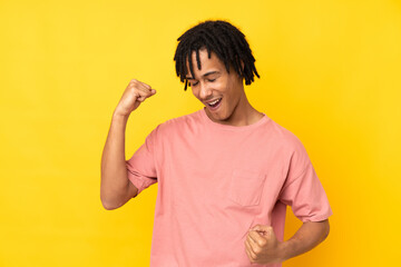 Young african american man isolated on yellow background celebrating a victory