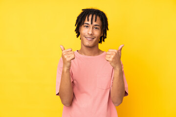 Young african american man isolated on yellow background with thumbs up gesture and smiling