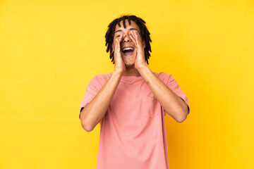 Young african american man isolated on yellow background shouting and announcing something
