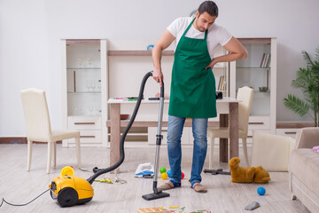 Young male contractor cleaning the flat after kids' party