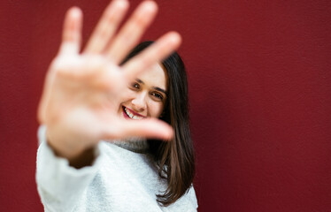 Close up photo of smiling woman making high and showing five with her hand.